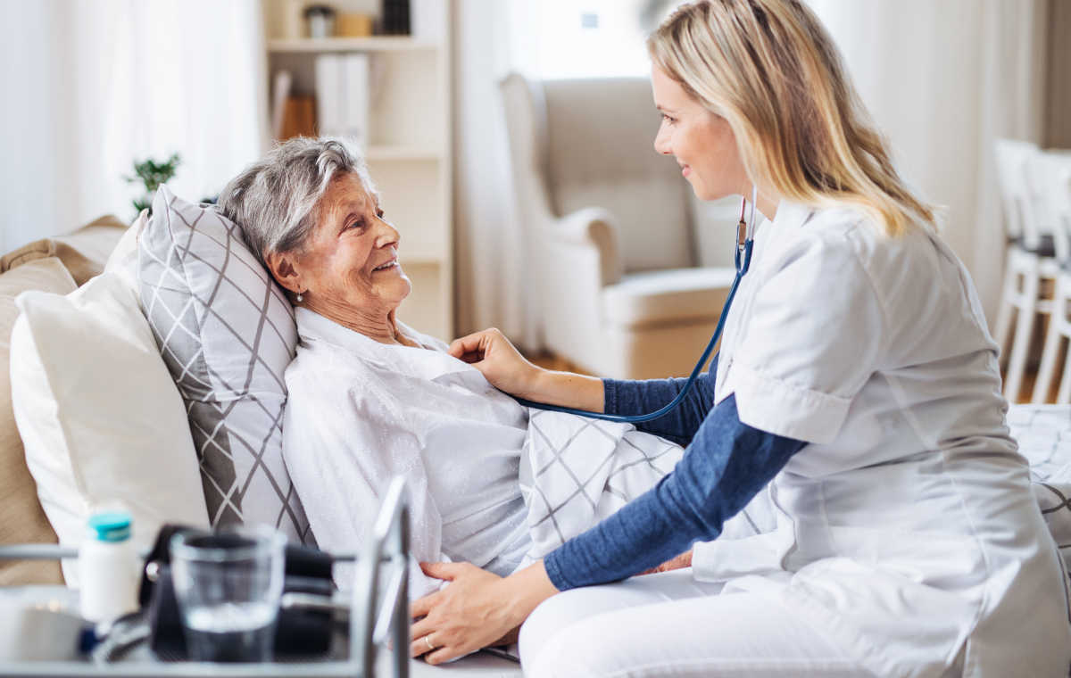 Pflegehilfe beim Anziehen einer älteren Person im Alltag