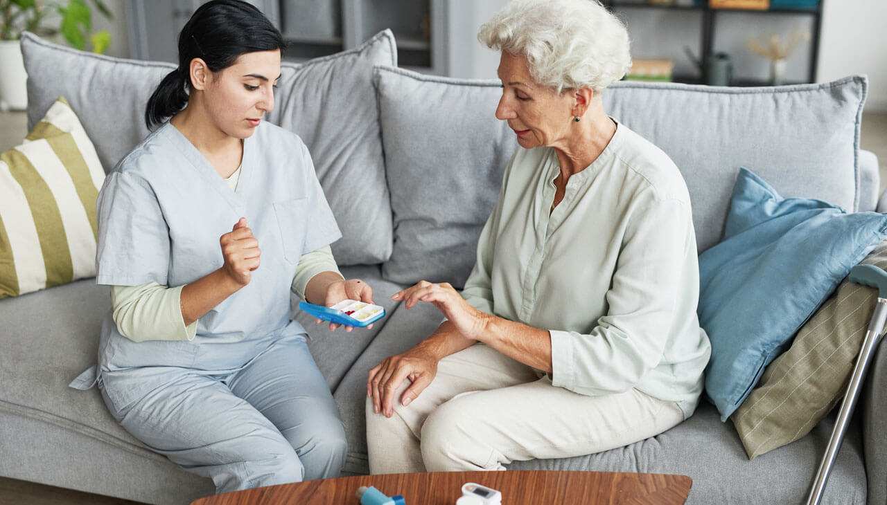 Senior wird beim Gehen in der Wohnung unterstützt durch Pflegekraft